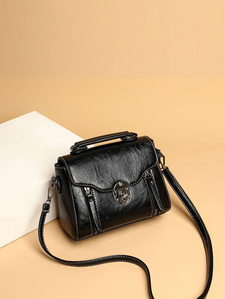 Black handbag with a strap on a beige background