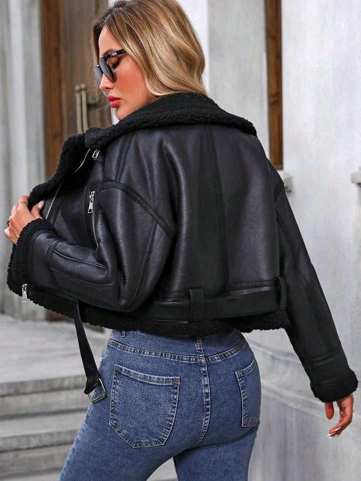 Woman wearing a black leather jacket with fur lining and blue jeans, standing outdoors.