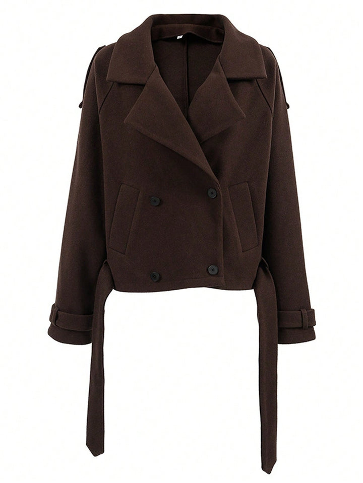 A dark brown cropped double-breasted coat with wide lapels, front flap pockets, and matching tie belts at the cuffs, shown on a plain white background.