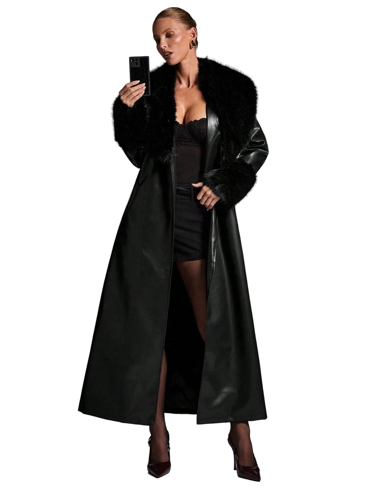 Woman wearing a long black coat with fur collar against a gray background