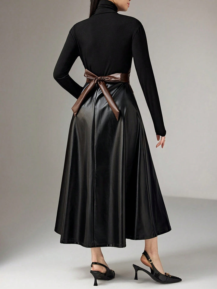 A model from the back wearing a black long-sleeve mock-neck dress with a brown faux-leather waist sash tied in a bow, paired with black slingback heels.