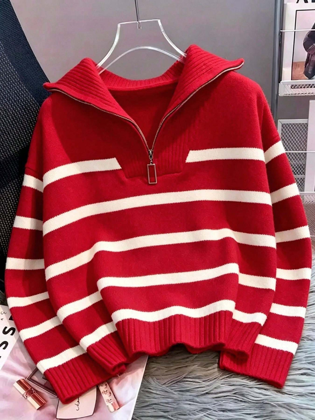 A red and white horizontally striped knit sweater with a half-zip mock neck collar, hanging on a clear plastic hanger.