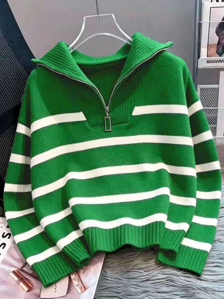 A green and white horizontally striped knit half-zip sweater with a mock neck and ribbed cuffs and hem, hanging on a clear plastic hanger.