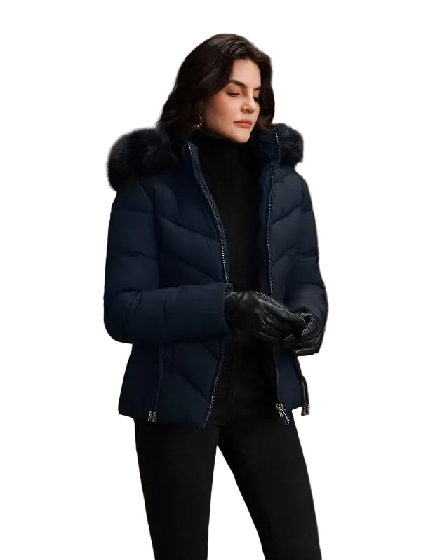 Person wearing a navy blue puffer jacket with fur hood on a brown background