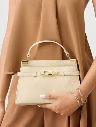 Beige handbag held by a person wearing a brown dress.